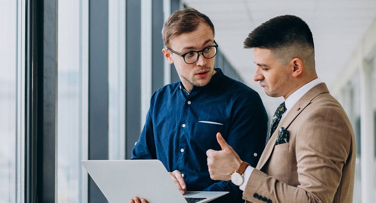 A person showing something to the another one in his laptop