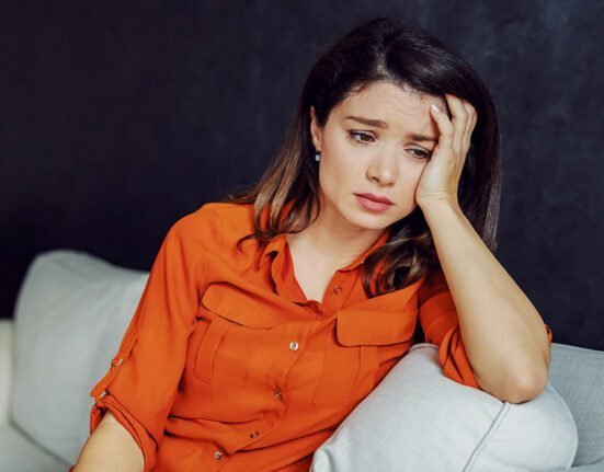 a girl wearing orange looking sad and thinking