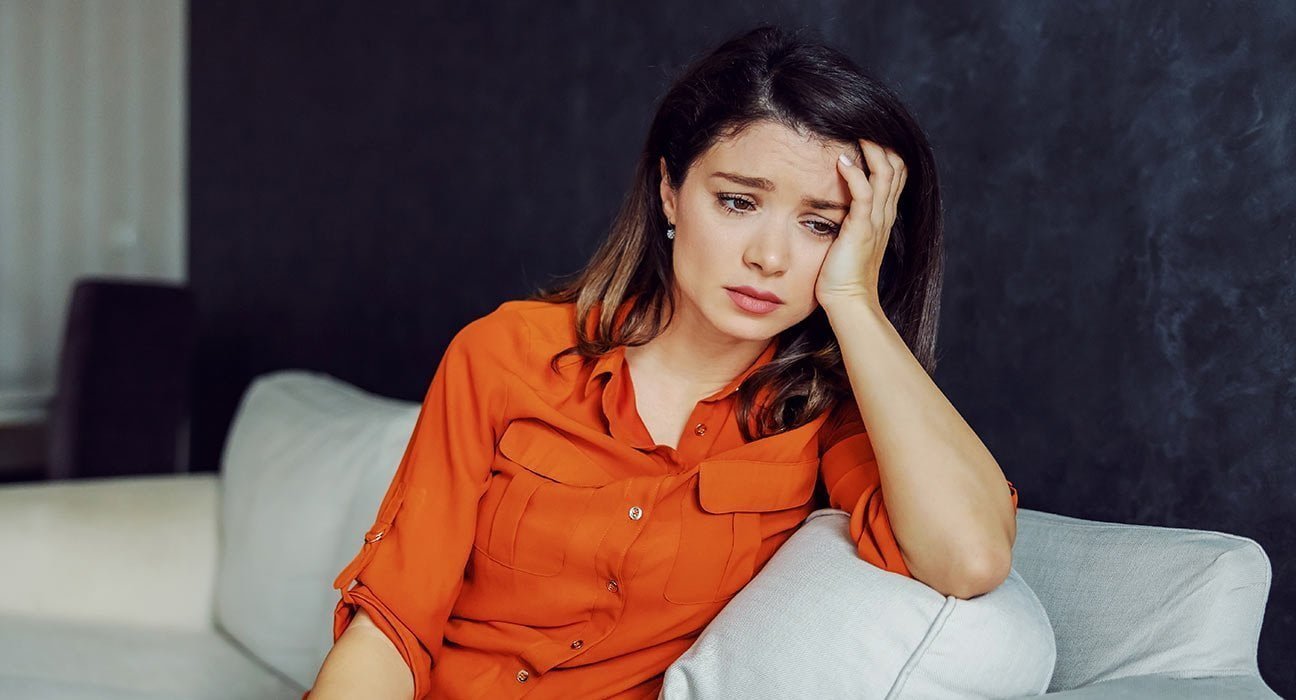 a girl wearing orange looking sad and thinking