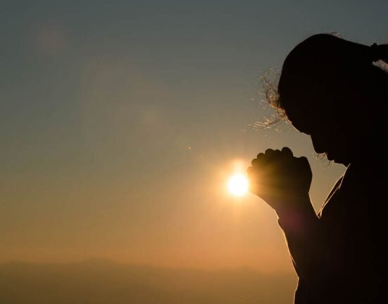 A girl praying in front of sun